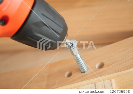 Close-up of power tool driving a screw into wood Close-up of power tool driving a screw into wood 126736908