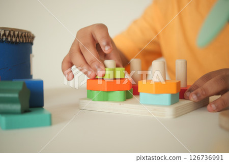 Child playing with colorful wooden shape sorting toys 126736991