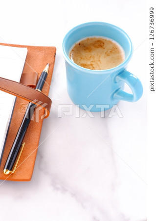 Image of a man working at his desk with a system organizer while drinking a cafe latte, a coffee with plenty of milk 126736999