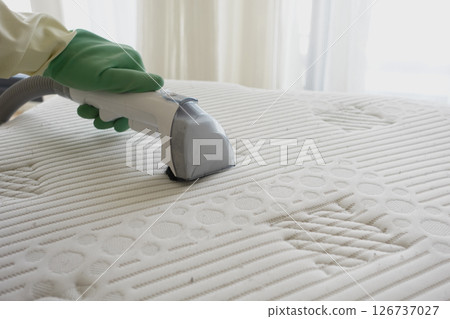 Cleaning a mattress with a steam cleaner in bright room 126737027