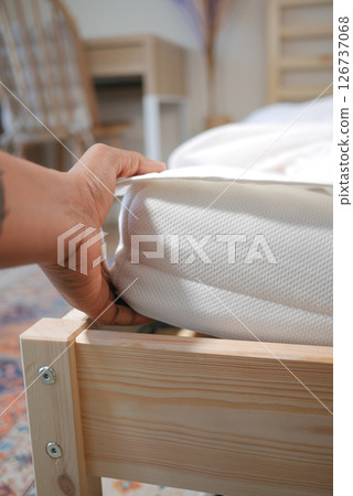 Adjusting a mattress in a cozy bedroom setting 126737068