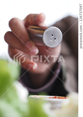 Hand sprinkling seasoning over a fresh salad mix Hand sprinkling seasoning over a fresh salad mix 126737097