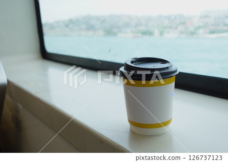 Coffee cup on a windowsill with a waterfront view 126737123