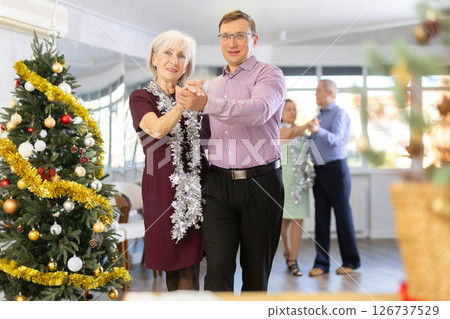 Middle-aged man and elderly woman dancing contemporary discofox in couple in New Year atmosphere 126737529