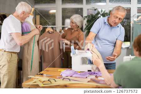 Instructor of tailoring course for seniors reviewing patterns with participant 126737572
