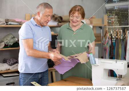 Senior man and woman communicate and discuss pattern, looking fabric blank billet at lesson 126737587
