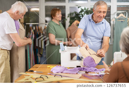 Instructor of tailoring course for seniors reviewing patterns with participant 126737655