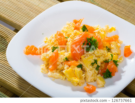 Cooked tasty omlette fried with salmon served at plate on table 126737661