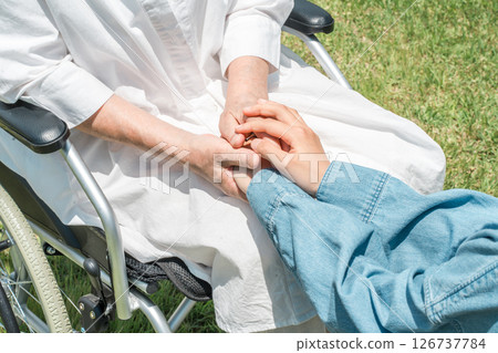 Granddaughter holding the hand of a senior woman sitting in a wheelchair 126737784