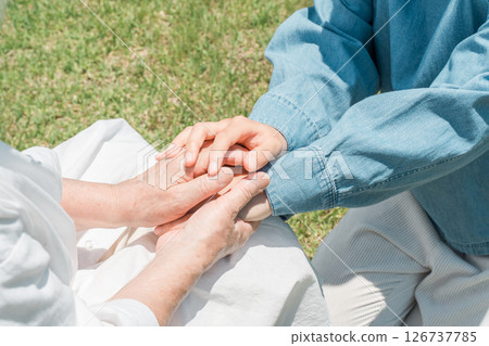 Granddaughter holding the hand of a senior woman sitting in a wheelchair 126737785