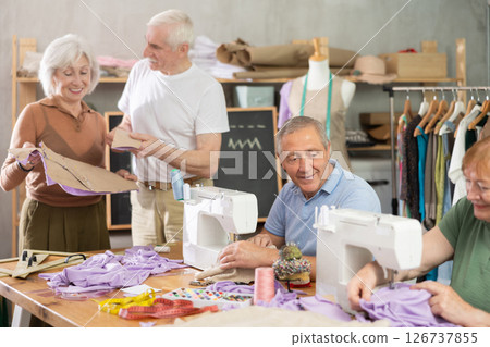 Elderly men and women sewing and discussing pattern in class 126737855