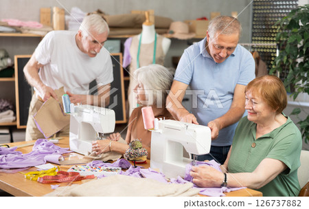 Elderly men and women spending time sewing in workroom Elderly men and women spending time sewing in workroom 126737882