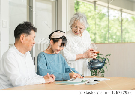 Grandmother and grandfather watching their granddaughter study (family, homecoming, homework) Grandmother and grandfather watching their granddaughter study (family, homecoming, homework) 126737952