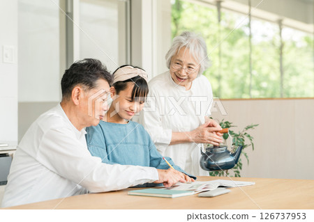 Grandmother and grandfather watching their granddaughter study (family, homecoming, homework) 126737953