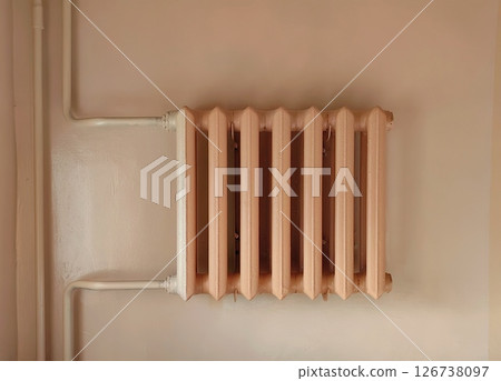 vintage radiator mounted on pale wall in an indoor setting showcasing retro heating design. closeup. 126738097