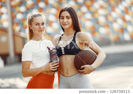 Beautiful girls at the stadium. Sports girls in a sportswear. People with baskettball ball. 126738513