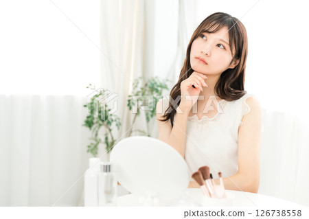 Young Asian woman worried about skin problems while looking in the mirror (skin care) 126738558