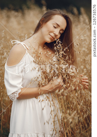 Woman in a summer field. Brunette in a white dress. Girl on a sunset background. 126738576