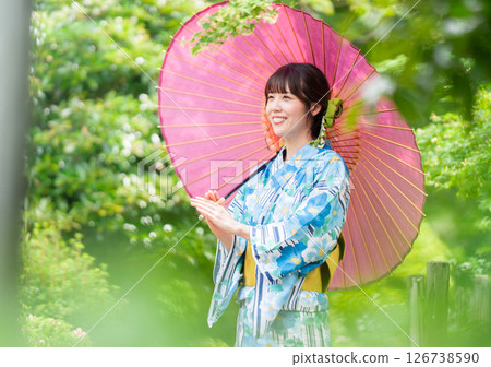一位身穿和服的年輕女子走過綠葉盛開的公園 126738590