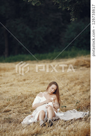 Mother with cute daughter. Mom breastfeeding her little daughter. Woman in a white dress. Mother with cute daughter. Mom breastfeeding her little daughter. Woman in a white dress. 126738617