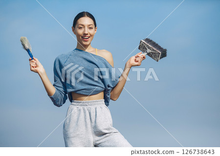 Beautiful girl standing on a sky background. Woman in a blue sweater. Lady with tools in her hands Beautiful girl standing on a sky background. Woman in a blue sweater. Lady with tools in her hands 126738643