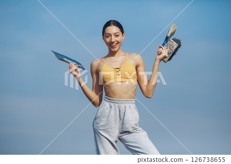 Beautiful girl standing on a sky background. Woman in a blue sweater. Lady with tools in her hands 126738655