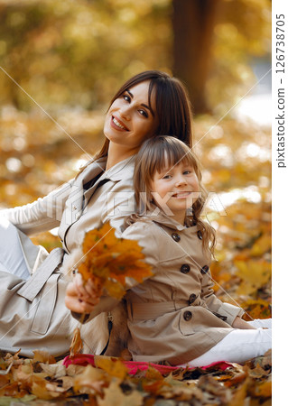 Fashionable mother with daughter. Family in a autumn park. Little daughter in a brown coat. 126738705