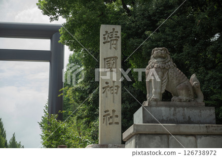 [Japan] A stone pillar with the name of the shrine carved in it and a stone lion statue erected in front of the torii gate of Yasukuni Shrine in Chiyoda Ward, Tokyo 126738972