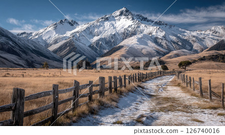 Snowy mountain range towers over rolling hills and rustic path under clear skies, capturing untouched beauty of South Island, New Zealand Snowy mountain range towers over rolling hills and rustic path under clear skies, capturing untouched beauty of South Island, New Zealand 126740016