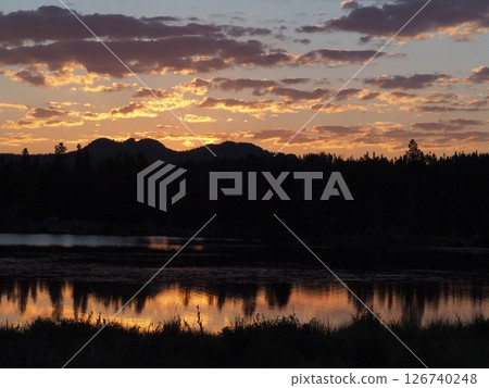 Mountain scenery reflected in a calm lake at dawn Mountain scenery reflected in a calm lake at dawn 126740248