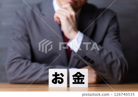 一位身穿西裝、頭戴錢袋的中年男性商人感到憂心忡忡 一位身穿西裝、頭戴錢袋的中年男性商人感到憂心忡忡 126740535