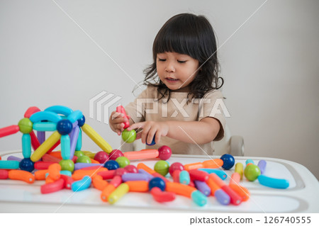 toddler girl playing colorful magnetic construction toy 126740555