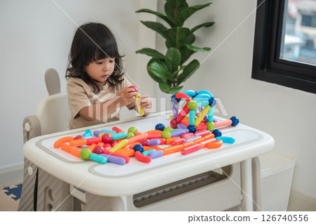 toddler girl playing colorful magnetic construction toy 126740556