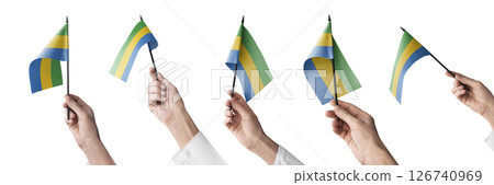 The Gabon flag in hand in different angles on a white background 126740969