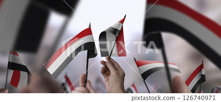 Yemen flags in their hands on a blurred urban background Yemen flags in their hands on a blurred urban background 126740971
