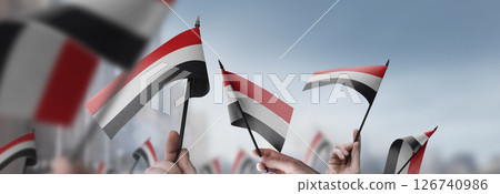 Yemen flags in their hands on a blurred urban background 126740986