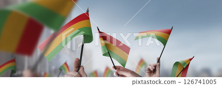 Bolivia flags in their hands on a blurred urban background Bolivia flags in their hands on a blurred urban background 126741005