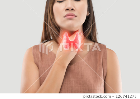 A woman holding her throat, illustrating potential thyroid pathology. A woman holding her throat, illustrating potential thyroid pathology. 126741275
