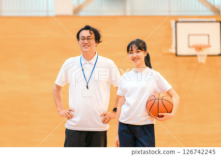一名男老師和一名女學生在體育館拿著籃球 126742245