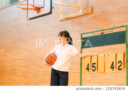 一名身穿運動服的女學生在體育館翻動記分牌 126742654
