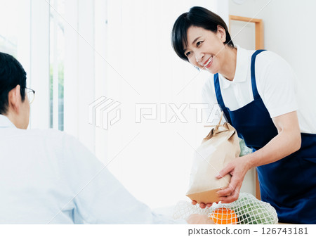 一位女家政人員正在餐桌上擺放食材 126743181