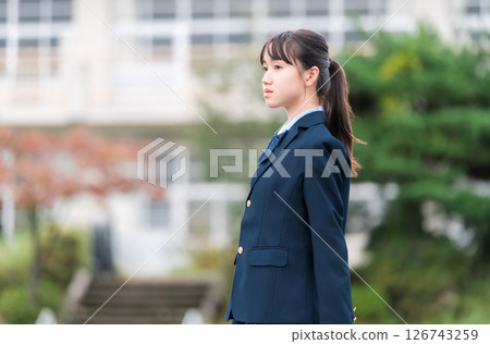 Junior high school, high school, and elementary school students in uniform standing in front of the school building 126743259
