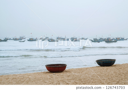 Vietnamese traditional round baskets boats Thung Chai on beach and ships at sea in a fishing village in Vietnam Vietnamese traditional round baskets boats Thung Chai on beach and ships at sea in a fishing village in Vietnam 126743703