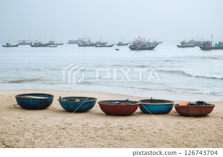 Vietnamese traditional round baskets boats Thung Chai on the beach and ships at sea in a fishing village in Vietnam 126743704