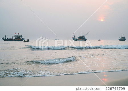 Vietnamese fishing ships and boats at sea in the morning at sunrise in a fishing village in Vietnam Vietnamese fishing ships and boats at sea in the morning at sunrise in a fishing village in Vietnam 126743709