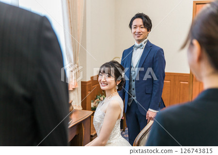 新娘和新郎在婚禮場地的新娘房和等候室與工作人員、經理和父親交談 126743815