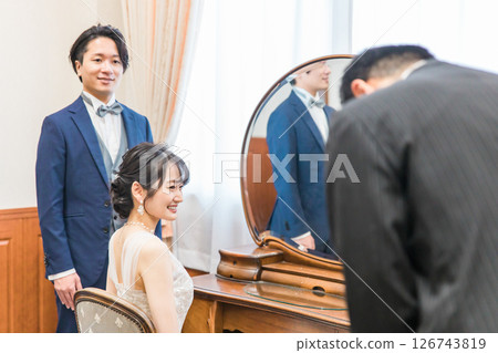 Bride and groom talking to staff, manager and father in the bridal room and waiting room of the wedding venue 126743819