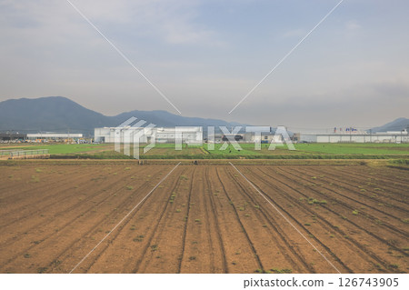 March 28 2025 Wide Agricultural Fields near Industrial Buildings with Mountains March 28 2025 Wide Agricultural Fields near Industrial Buildings with Mountains 126743905