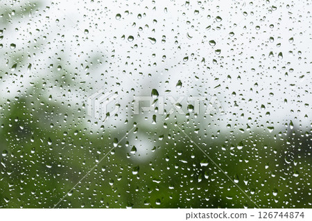 Raindrops scatter across a clear windowpane, macro photo 126744874