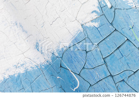 An abstract close-up of a cracked surface, featuring blue and white paint 126744876